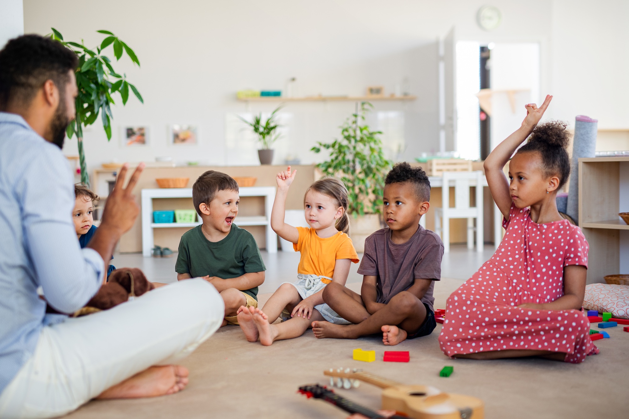 Group of small nursery school children sitting on floor indoors in classroom